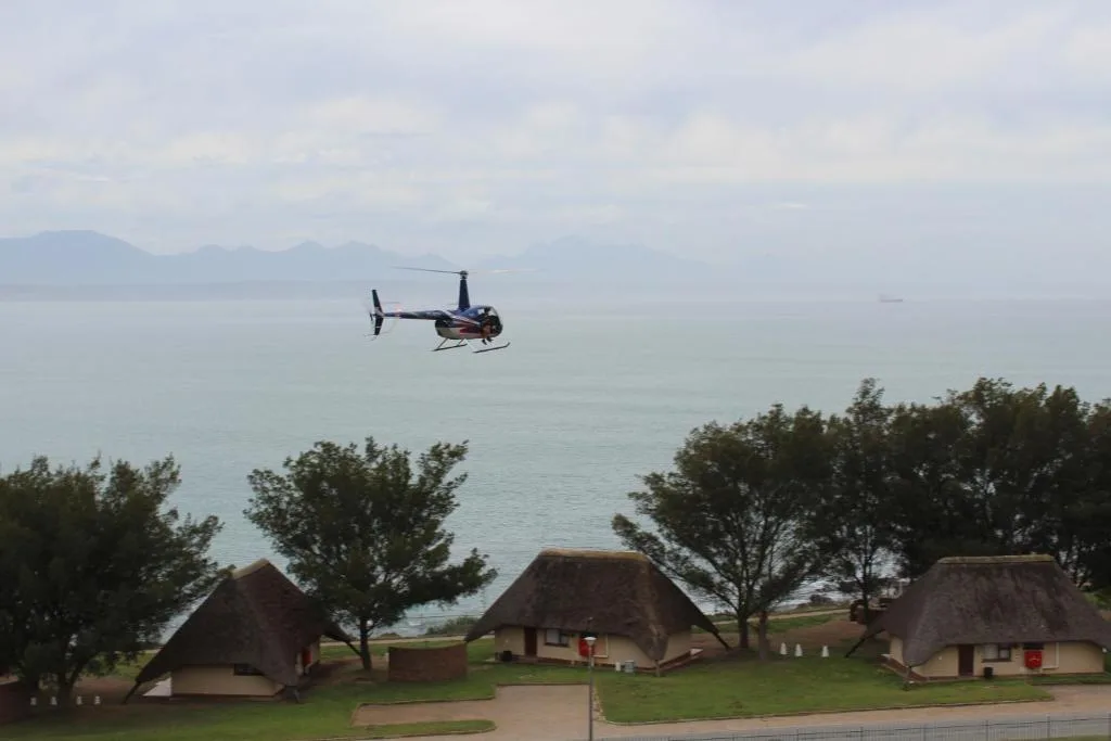 Scenic coastal view with helicopter over turquoise waters and mountains