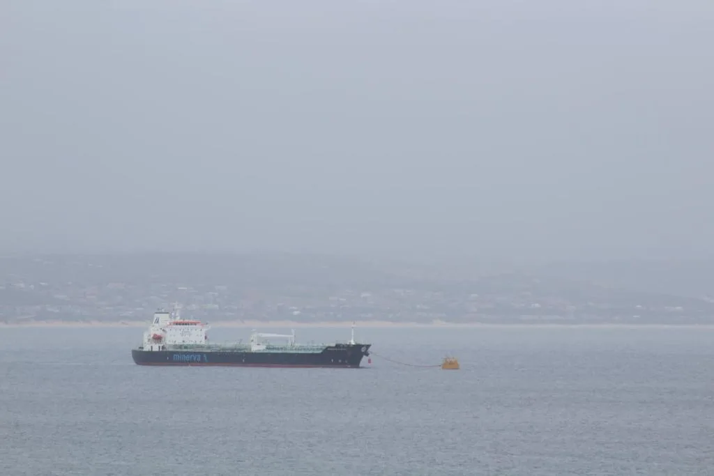 Cargo ship on calm ocean waters with hazy coastal landscape beyond
