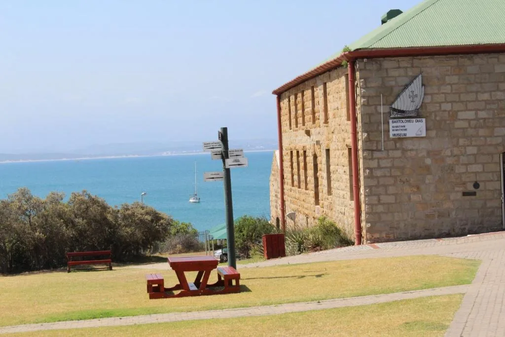 Turquoise ocean and coastline visible beyond historic stone building and manicured gardens