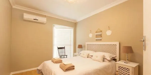 Warm bedroom with queen bed, pendant lights, and air conditioning unit