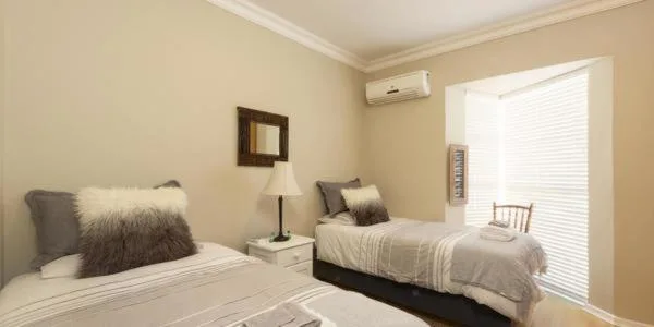 Twin beds with neutral bedding and decorative pillows in bright bedroom