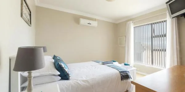 Bright bedroom with white bed, bedside lamp, and sliding door views