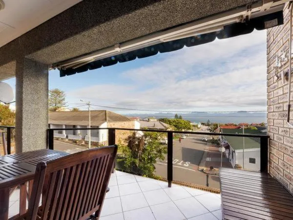 Covered deck with wooden chairs overlooking coastal town and bay