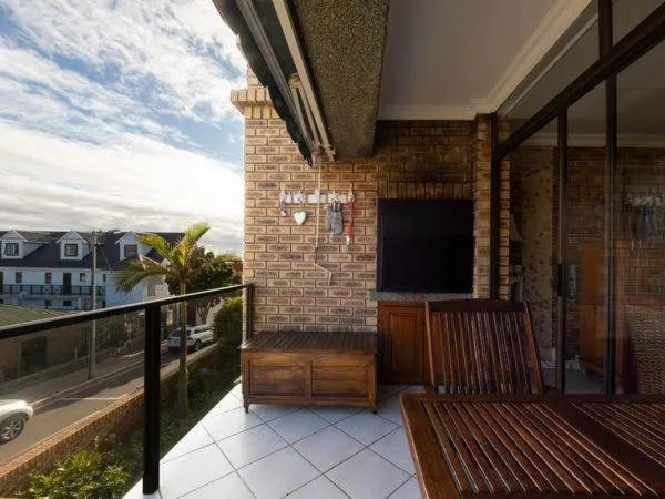 Spacious outdoor deck with wooden seating and coastal views