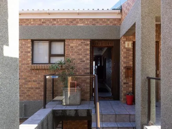 Modern brick apartment entrance with paved courtyard and potted plants