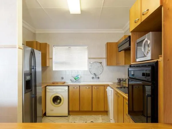 Compact kitchen with wooden cabinetry, stainless steel appliances, and washing machine