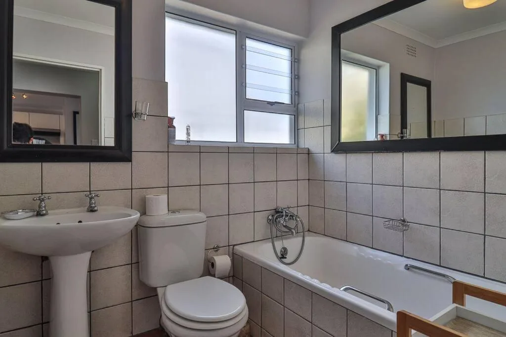 Bathroom with dual vanities, toilet, bathtub, and large mirrors