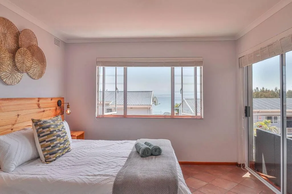 Bedroom with wooden headboard and water views through large windows