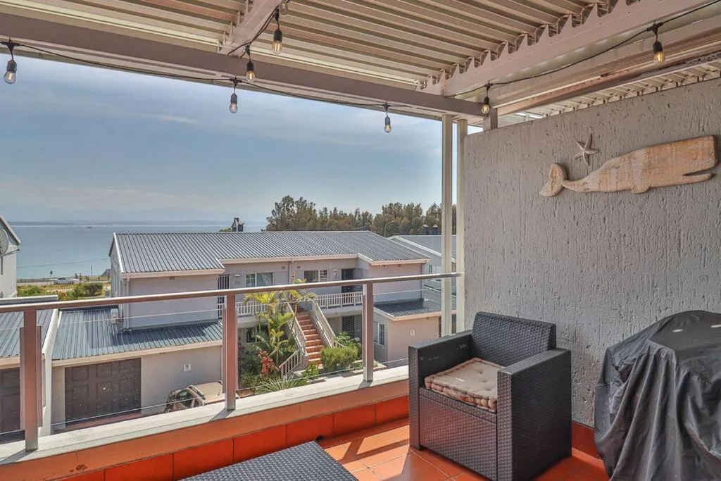 Covered patio with sea views, lounge chairs, and coastal scenery beyond