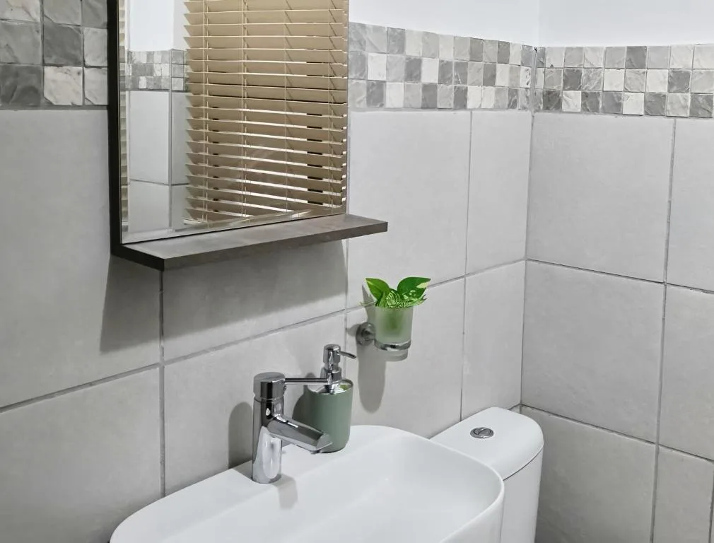 Modern bathroom with white tiles, vanity sink, and decorative green accents