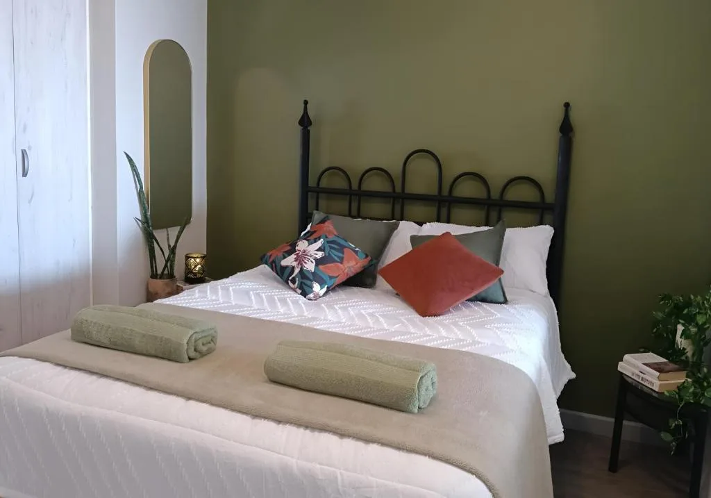 Tastefully decorated bedroom with black iron bed frame and sage green walls