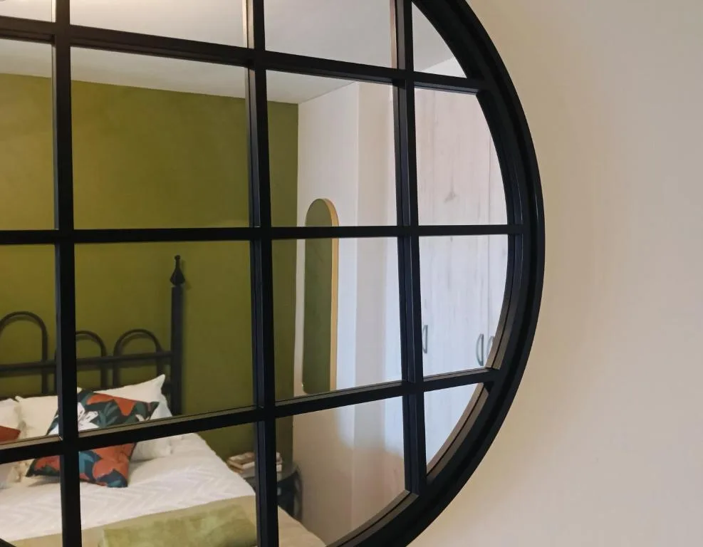 Modern bedroom with olive green walls viewed through contemporary black-framed glass partition