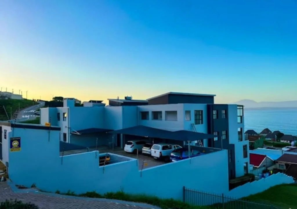 Modern blue and white apartment building with ocean views and carport parking