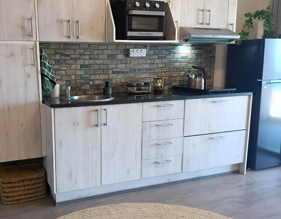 Modern kitchen with white cabinetry, black countertop, and brick backsplash