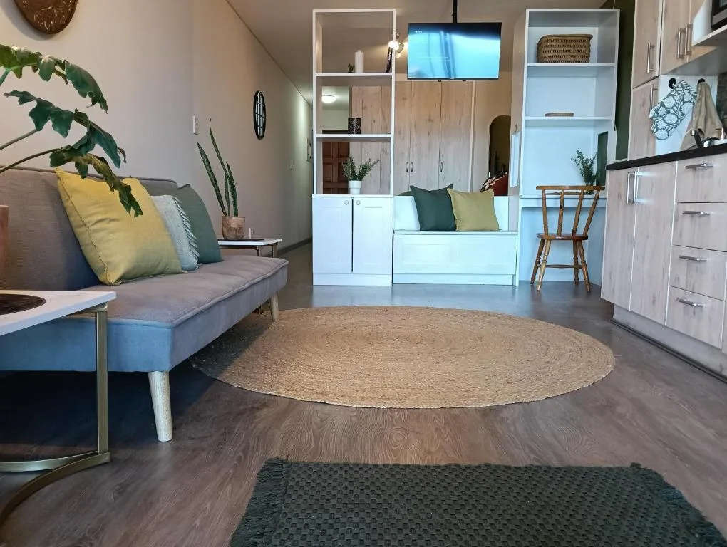 Modern lounge with gray sofa, colorful pillows, round jute rug, and wall-mounted TV.