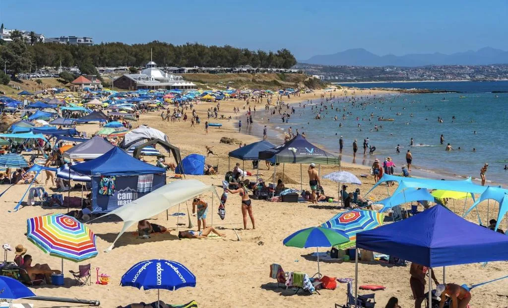 Scenic beach view with swimmers and colorful umbrellas dotting golden sand