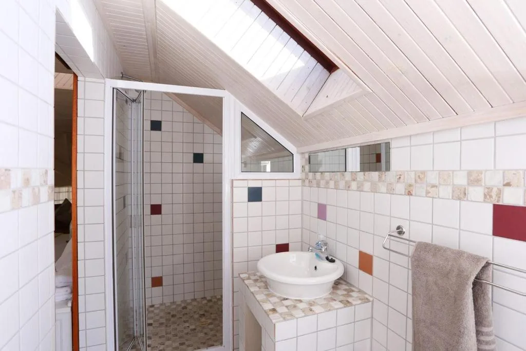 Modern bathroom with glass shower enclosure, round sink, colorful tile accents