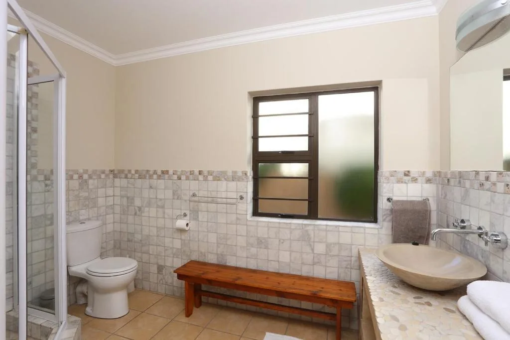 Spacious bathroom with tiled walls, vanity sink, toilet, and shower enclosure