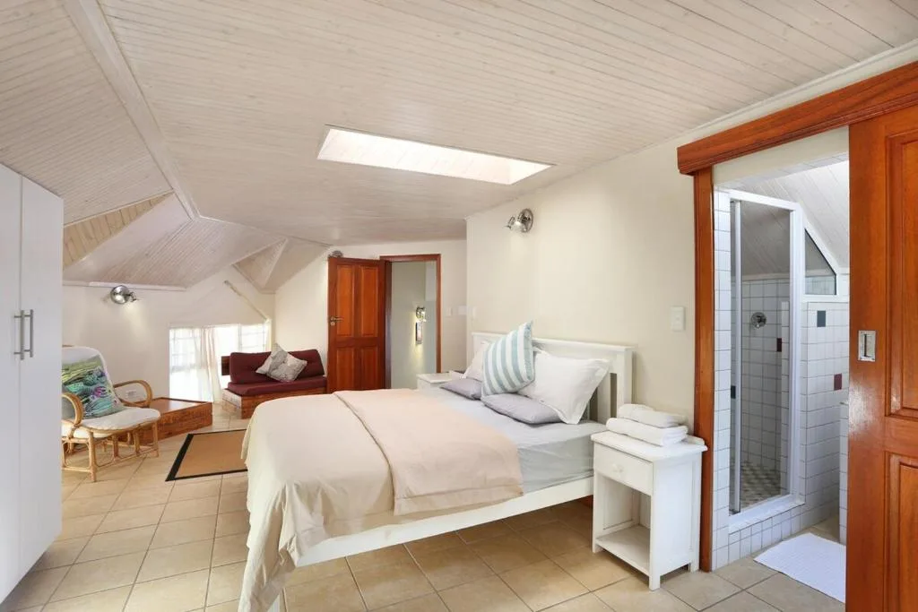 Spacious bedroom with queen bed, en-suite bathroom access, and lounge seating