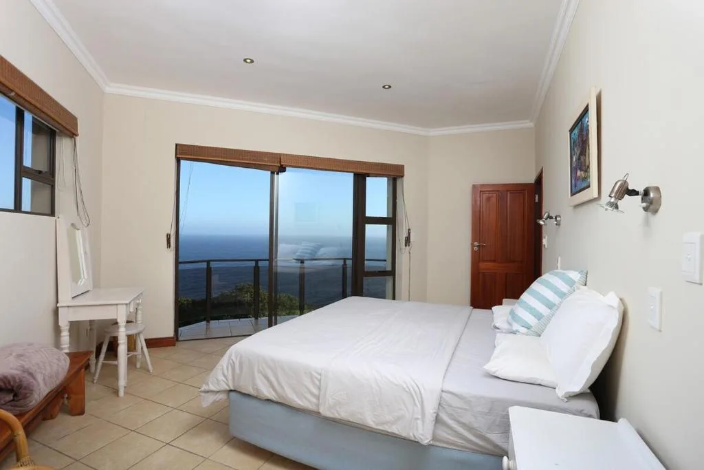 Spacious bedroom with ocean view through sliding glass doors and balcony