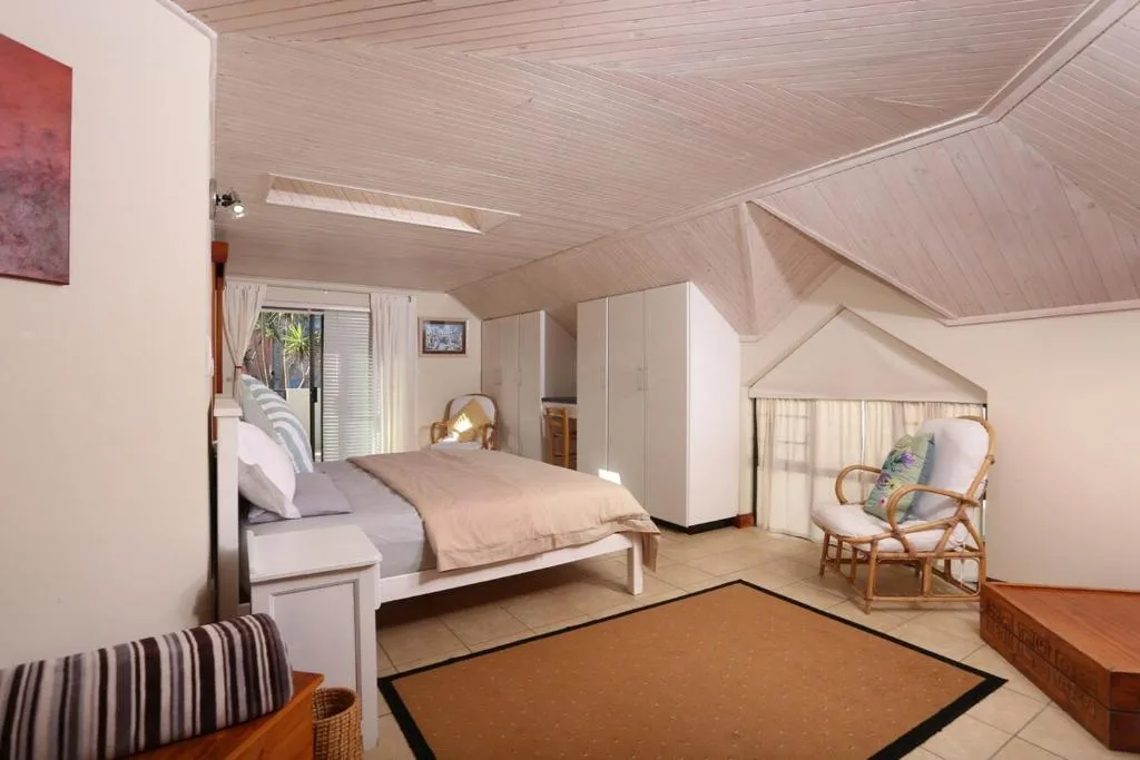 Spacious bedroom with queen bed, white wardrobe, and comfortable seating area