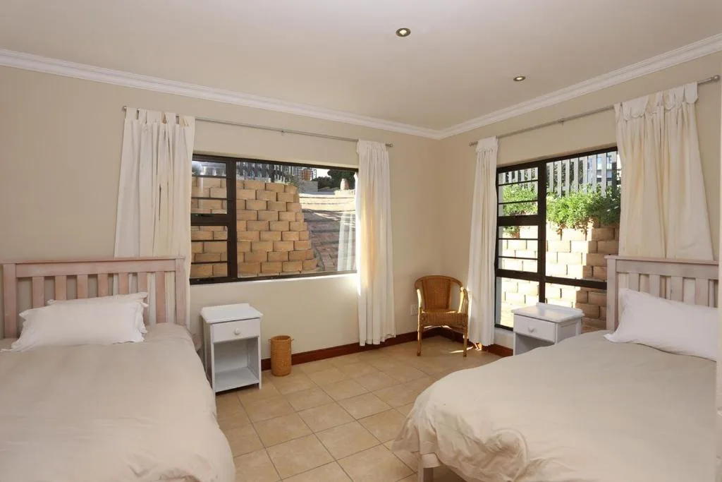 Spacious twin bedroom with cream walls, two beds, and garden access doors