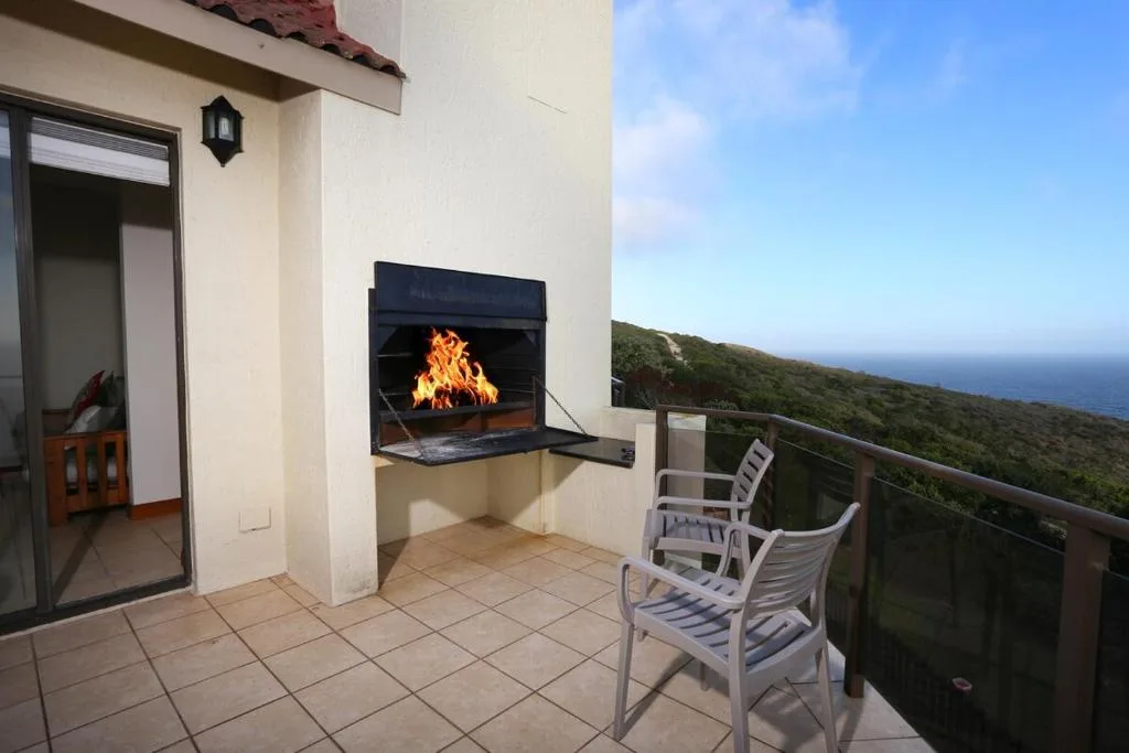 Outdoor deck with fireplace, seating, and ocean view beyond railing