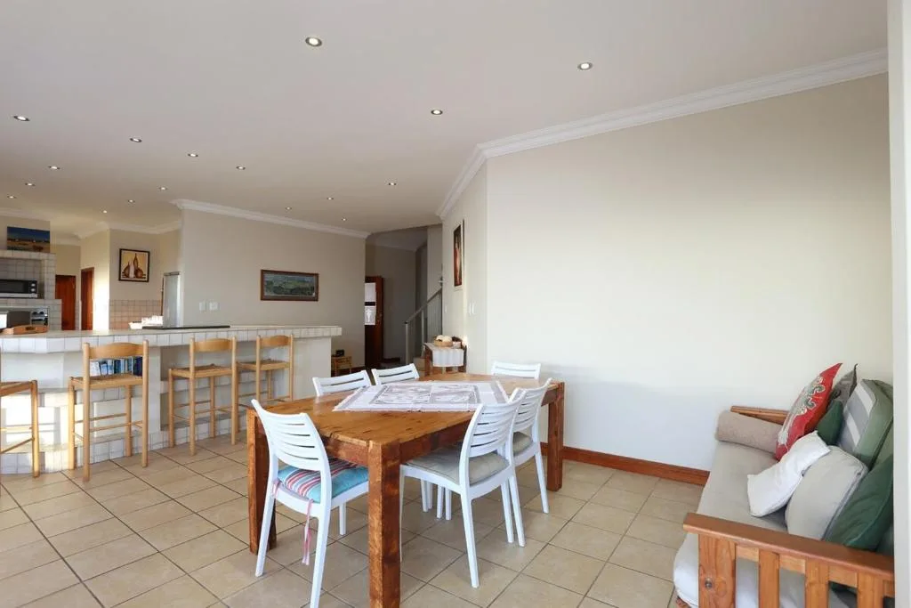 Wooden dining table with white chairs in open-plan living space