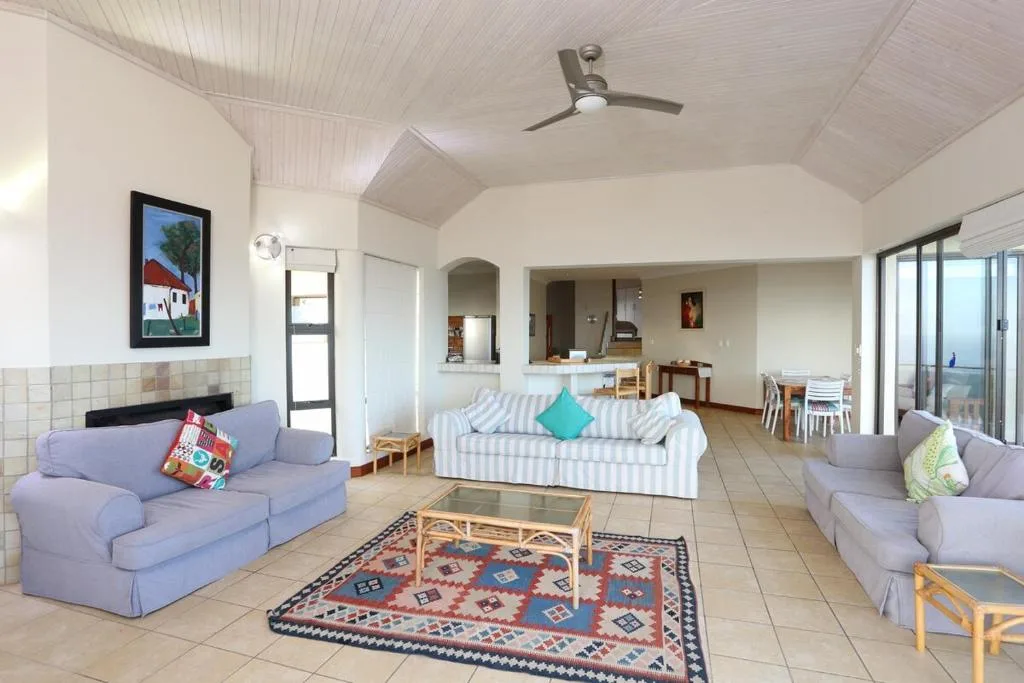 Spacious open-plan lounge with purple sofas and striped sofa, ceiling fan