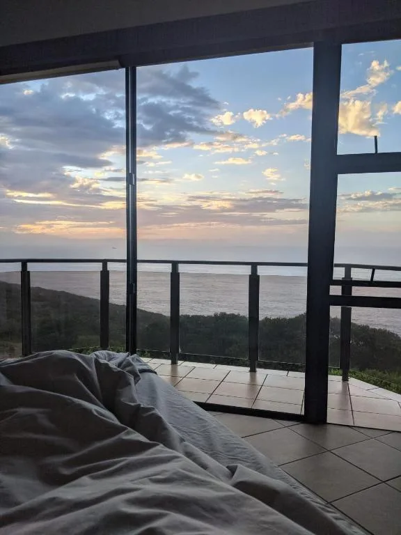 Dramatic coastal sunset view from bedroom with ocean and sky visible
