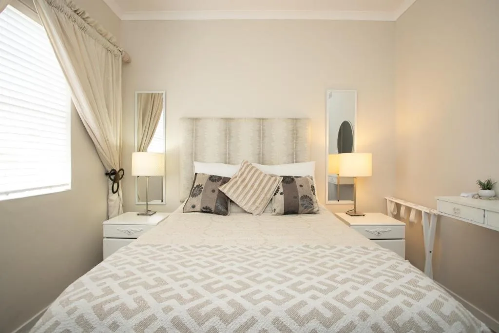 Neutral bedroom with queen bed, patterned bedding, and bedside lamps