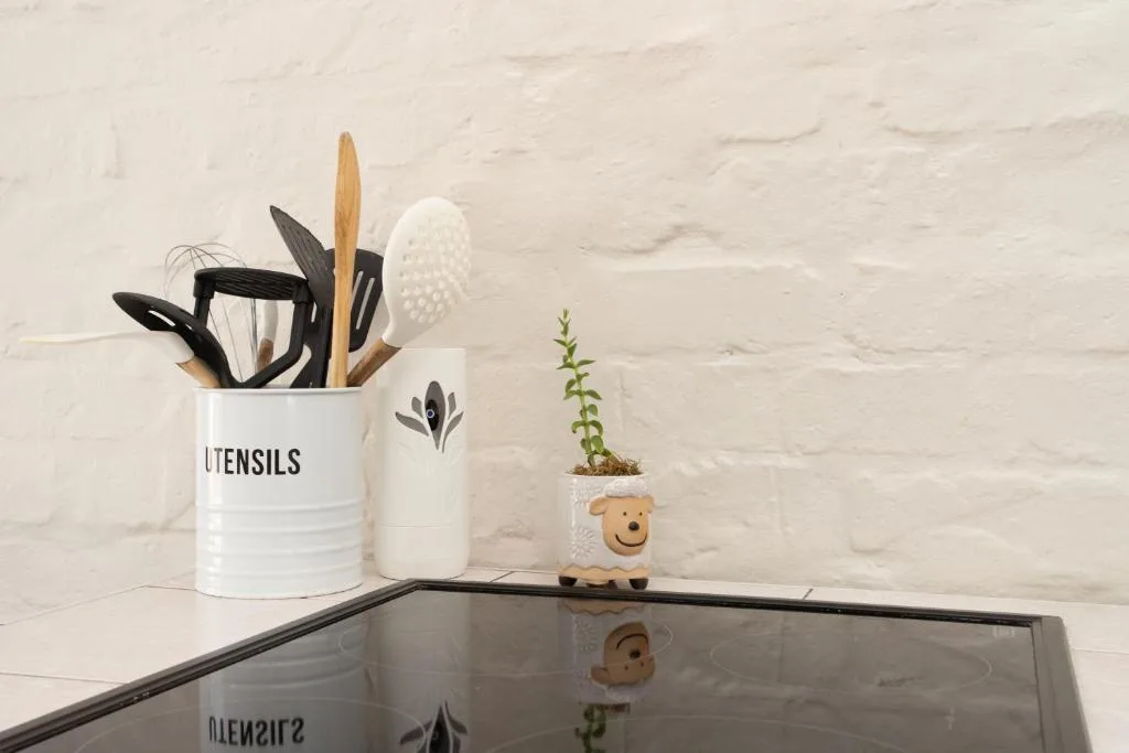 Kitchen counter styling with utensil holder, plant, and decorative items