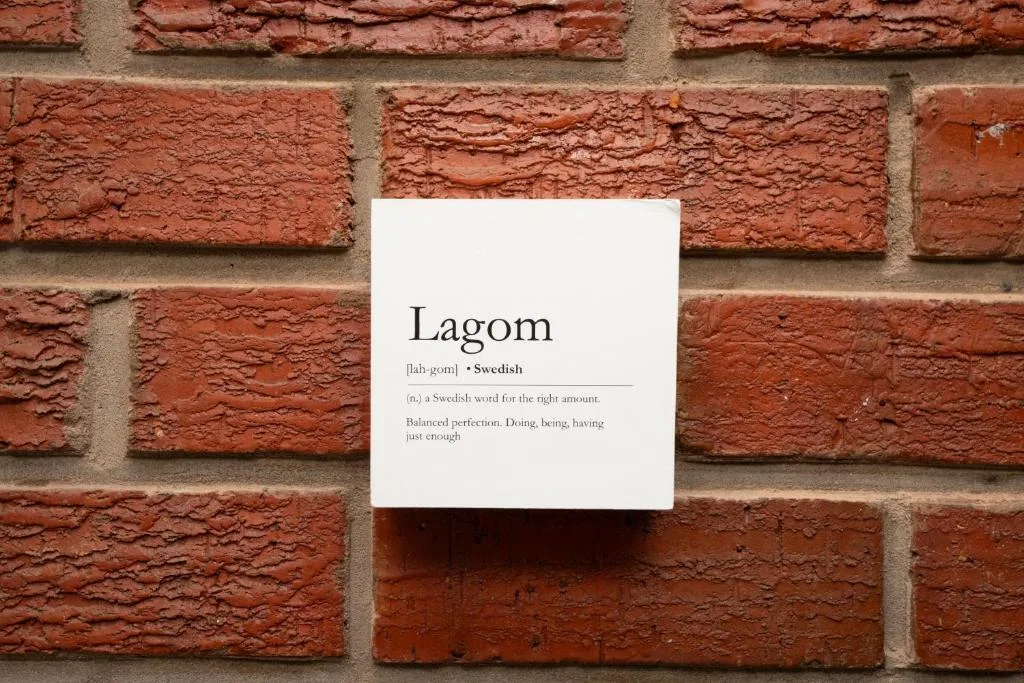 White card with Swedish word Lagom definition mounted on red brick wall