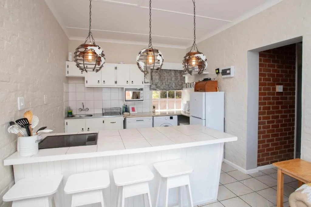 Modern white kitchen with island seating, pendant lights, and stainless appliances