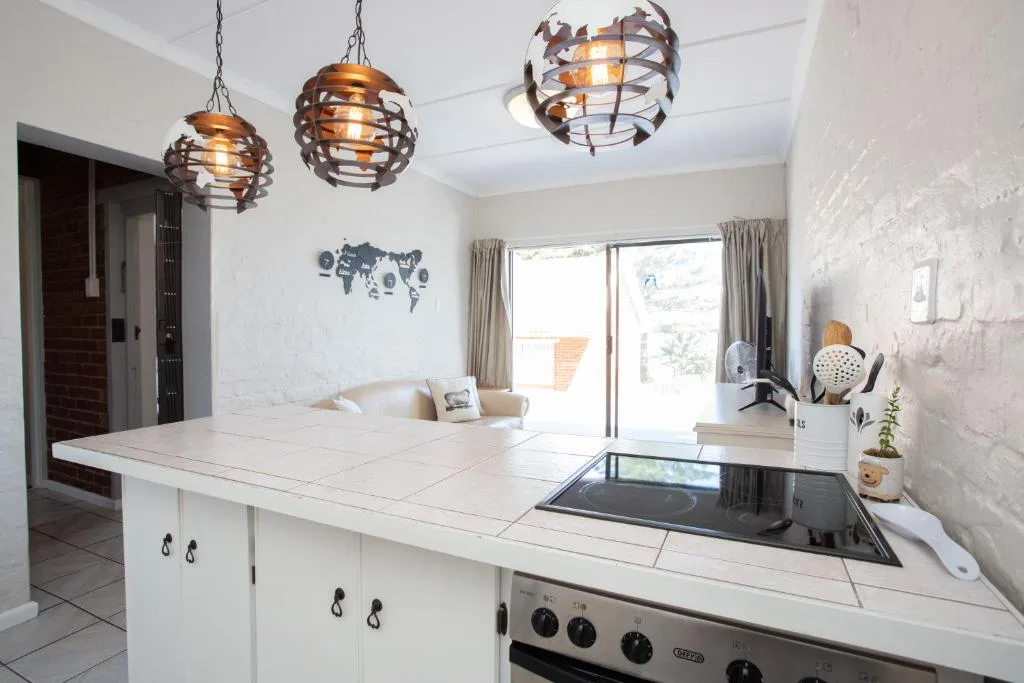 Modern open-plan kitchen with white cabinetry, induction cooktop, and decorative pendant lights