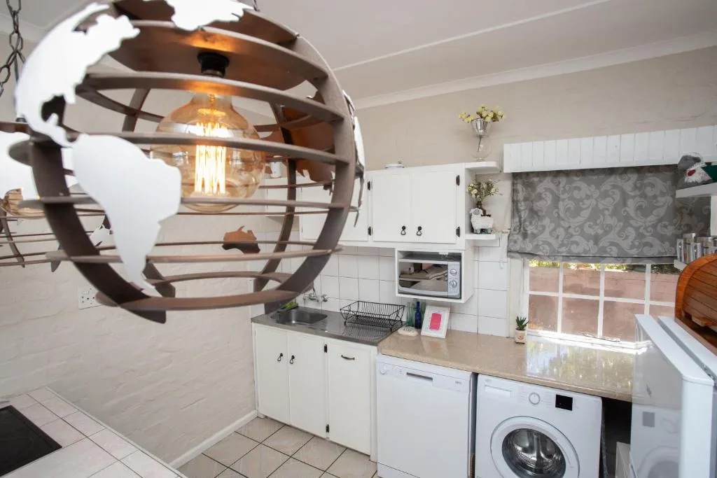 Modern kitchen with white cabinetry, washing machine, and decorative globe pendant light