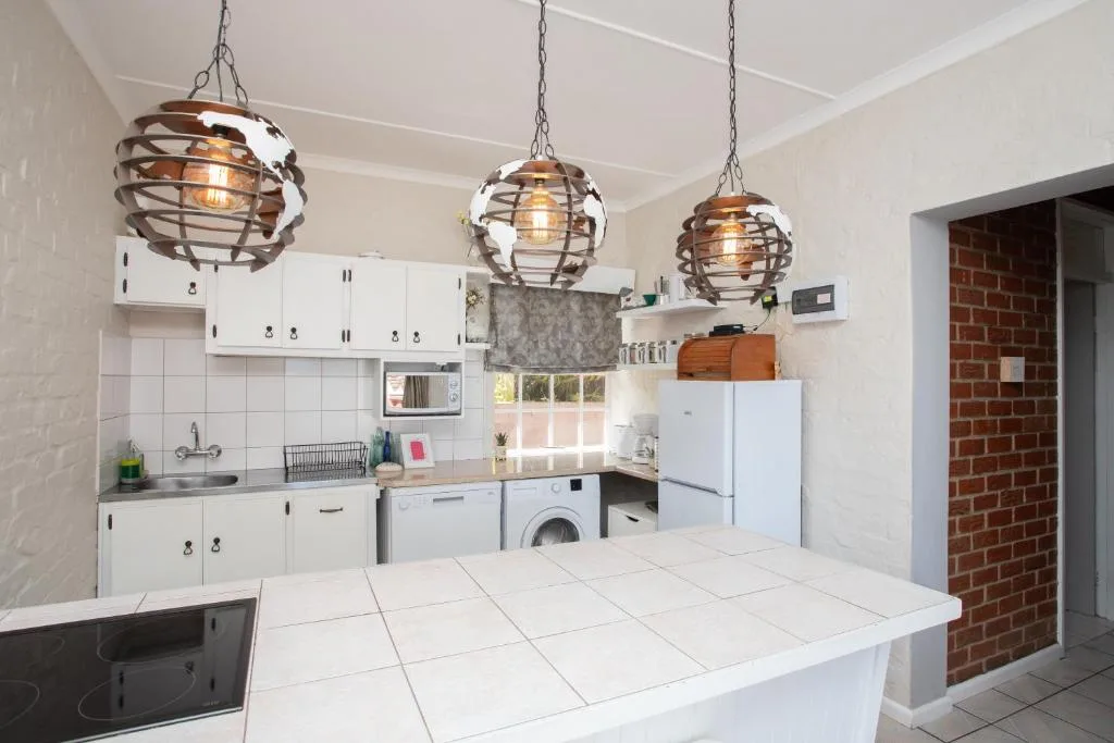 Modern kitchen with white cabinetry, industrial pendant lights, and tiled counters