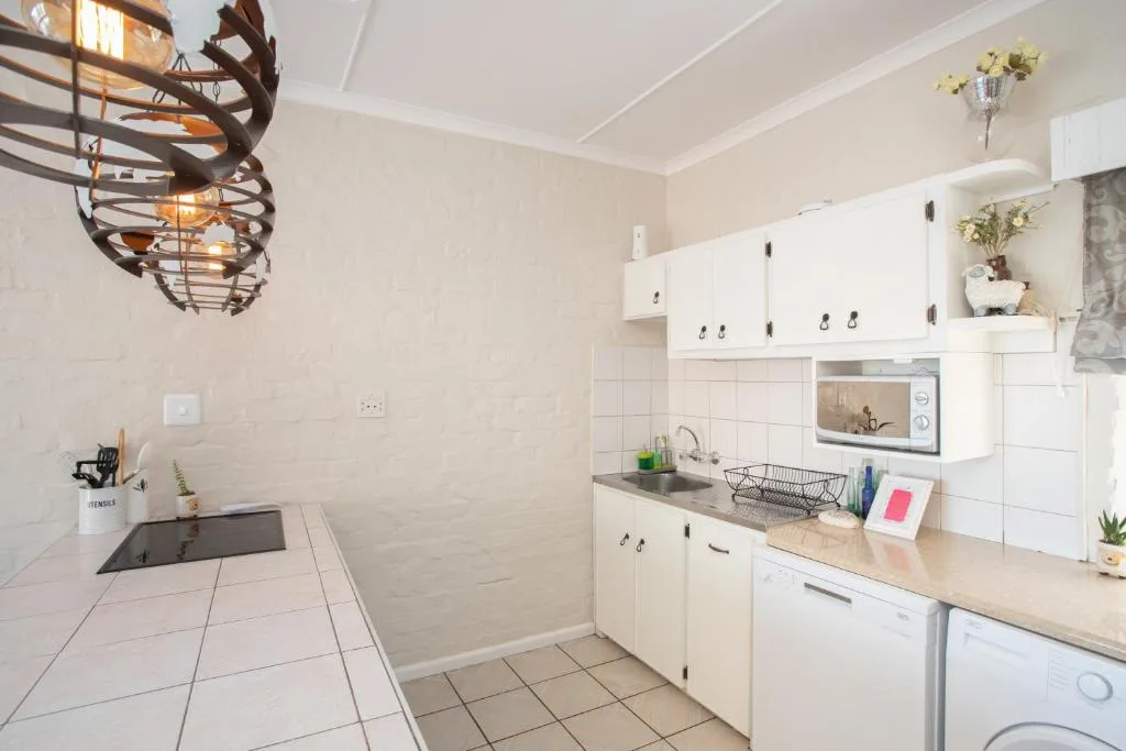 Bright kitchen with white cabinetry, tiled countertops, and decorative pendant light