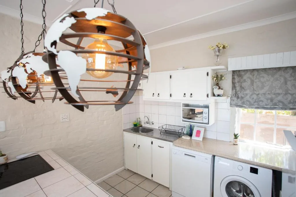 Modern kitchen with white cabinetry, washing machine, and decorative globe pendant light