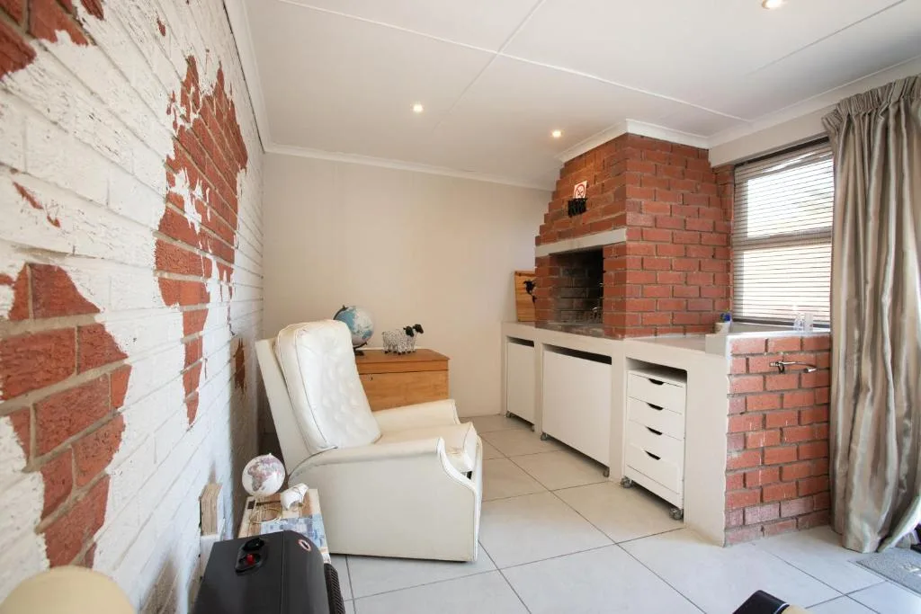 Spacious lounge with cream armchair, exposed brick fireplace, and natural light