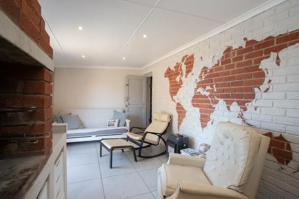 Modern lounge with cream armchairs, sofa, and world map brick wall art