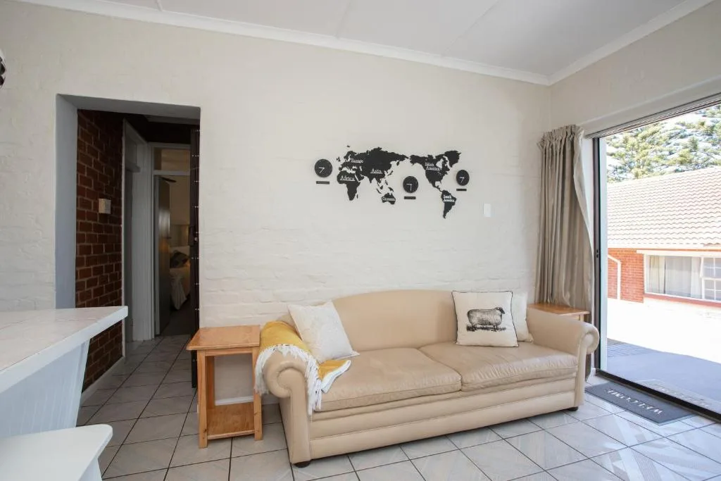 Spacious living room with cream sofa, wooden side table, and world map wall decor