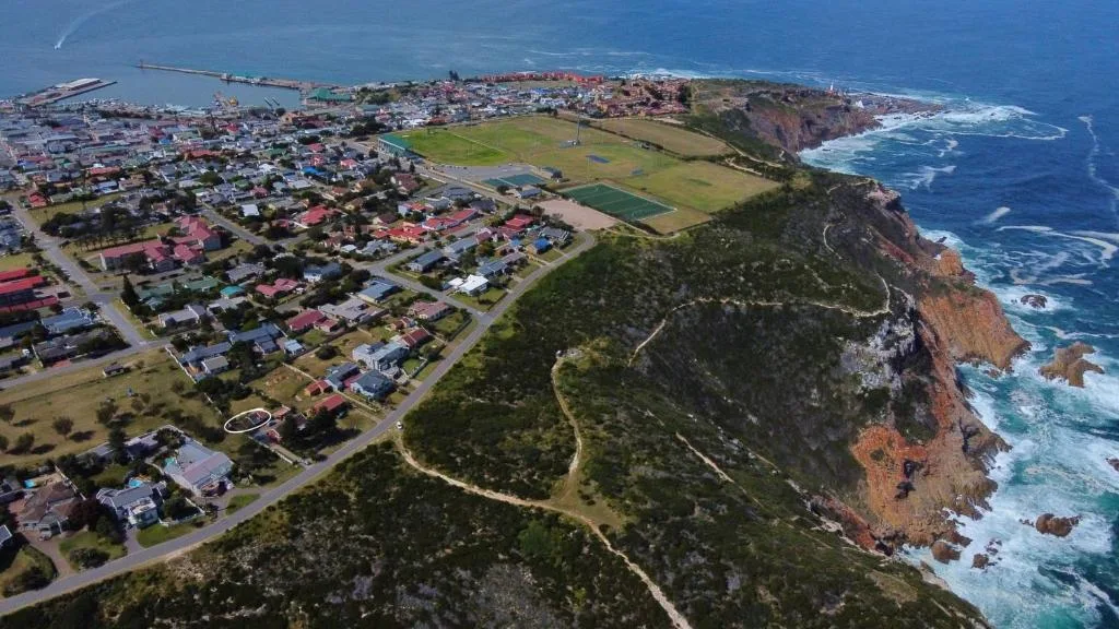 Aerial view of coastal town with cliffs, ocean, and residential properties below