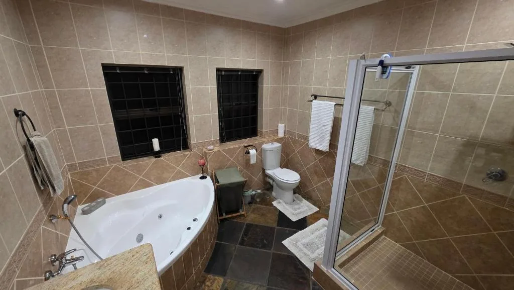 Spacious bathroom with corner bath, shower enclosure, and toilet