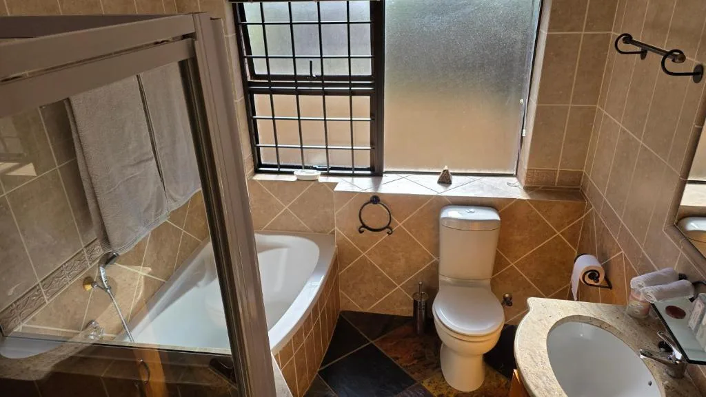 Bathroom with shower enclosure, toilet, and vanity sink with window