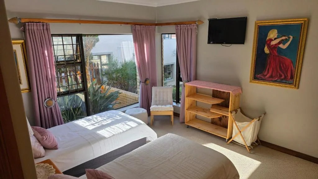Bright bedroom with two beds, pink curtains, and outdoor deck access views