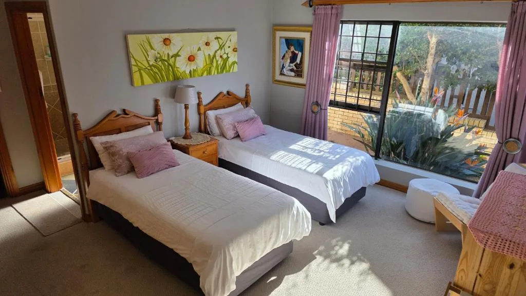 Twin bedroom with wooden beds, pink pillows, mountain views through glass doors