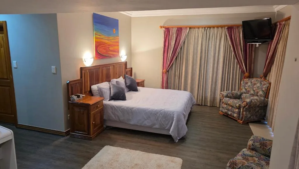 Spacious bedroom with wooden bed, armchair, and wall-mounted television