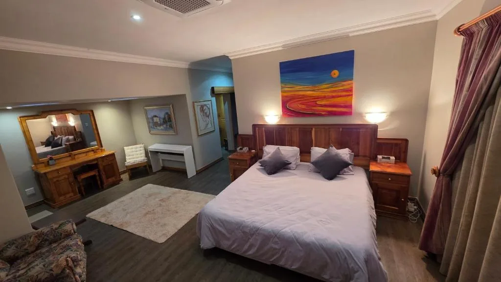 Spacious bedroom with queen bed, wooden headboard, and modern artwork above