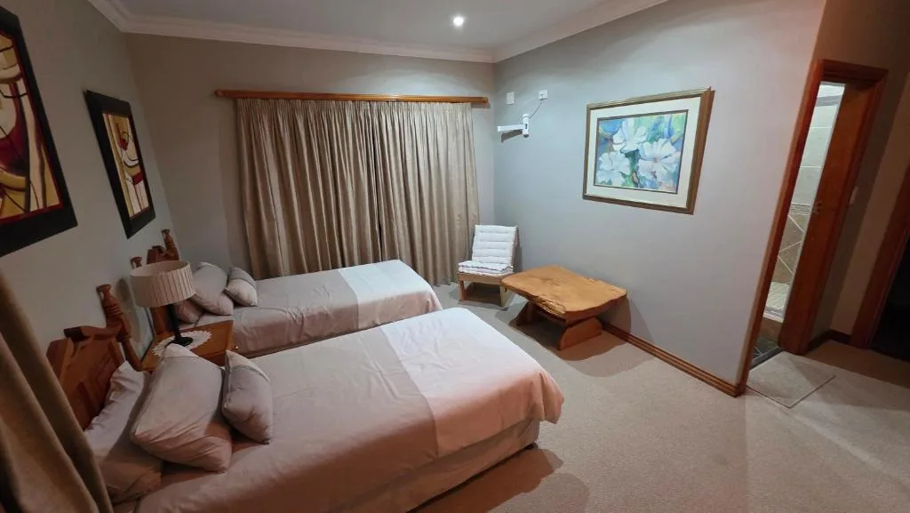 Spacious bedroom with two beds, wooden furniture, and large windows